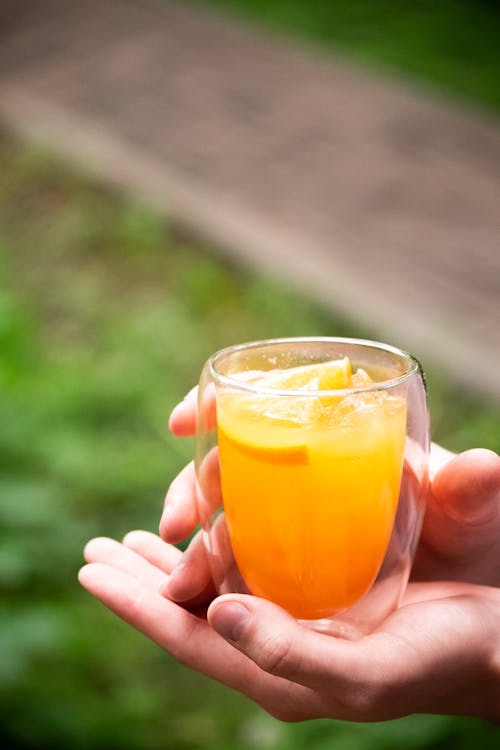 Free Person Holding Clear Drinking Glass With Orange Juice Stock Photo