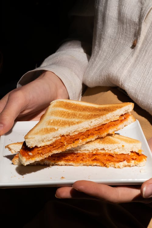 Person Holding Toasted  Bread on White Ceramic Plate