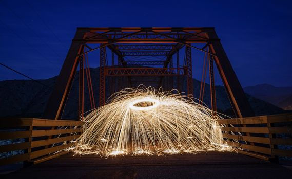 Captivating long exposure of steel wool light painting on bridge in Mentone, CA during night.
