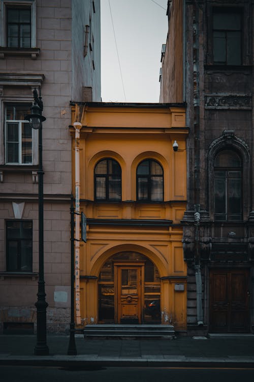 Orange Building between Tall Buildings · Free Stock Photo
