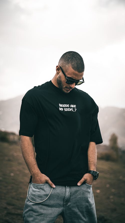 A Man in Black Shirt Wearing Sunglasses while Looking Down