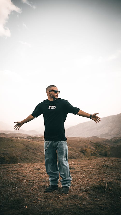 A Man in Black Shirt and Denim Jeans Standing on the Field