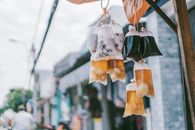 Plastic bags of drinks hanging in an urban street setting showcasing local street food culture.