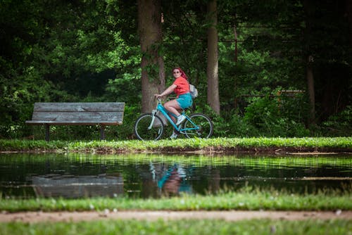 A Woman in Red Shirt Riding a Bicycle at the Park