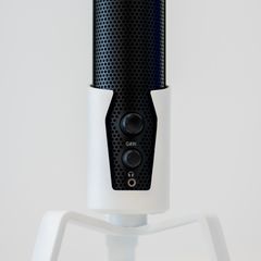A black mesh microphone with gain and headphone controls on a white stand