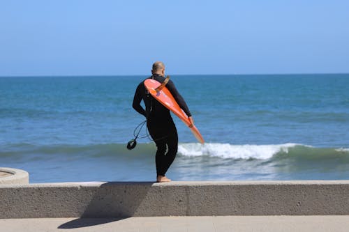 Back View of a Man Carrying a Surfboard