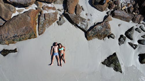 Free A Couple Lying on White Sand Stock Photo