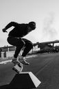 Man in Black Jacket and Pants Riding Skateboard in Grayscale Photography