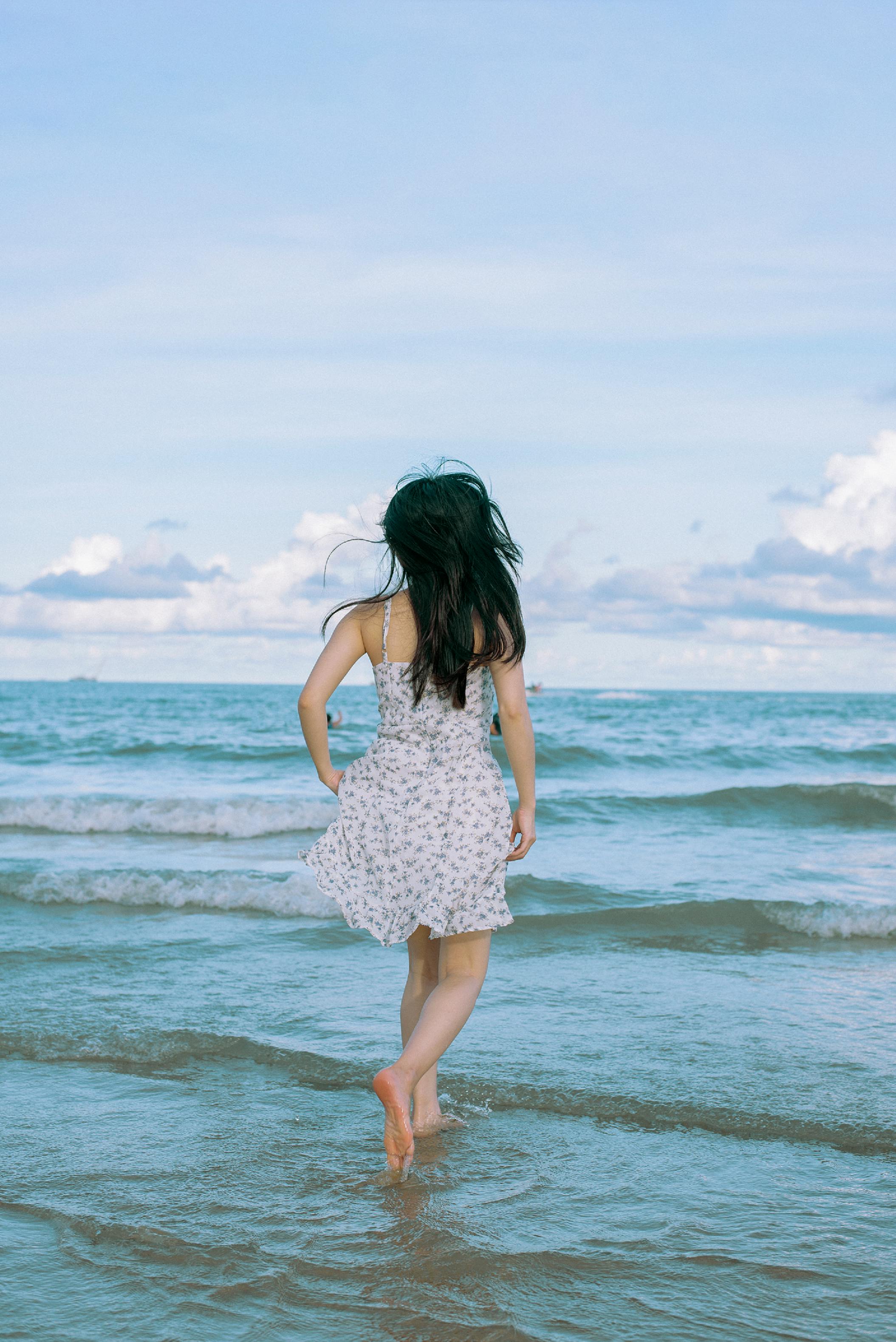 woman in sundress walking into sea