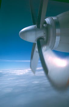 Detailed view of an airplane propeller spinning against a cloudy sky.