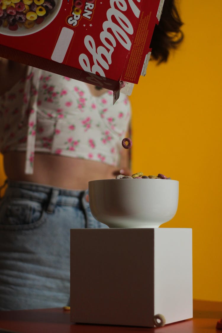 A Person Pouring Cereal On The Bowl