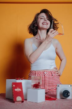 Smiling woman in trendy outfit enjoying a light-hearted moment indoors against a bright yellow background.