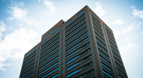 Free Low-angle view of a modern high-rise building against a bright blue sky in Cape Town, South Africa. Stock Photo