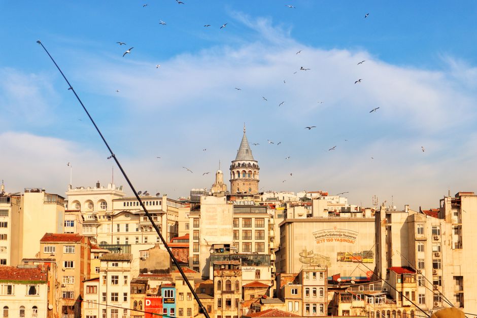 Stunning aerial image of Istanbul's Galata Tower under a clear blue sky, surrounded by urban cityscape.