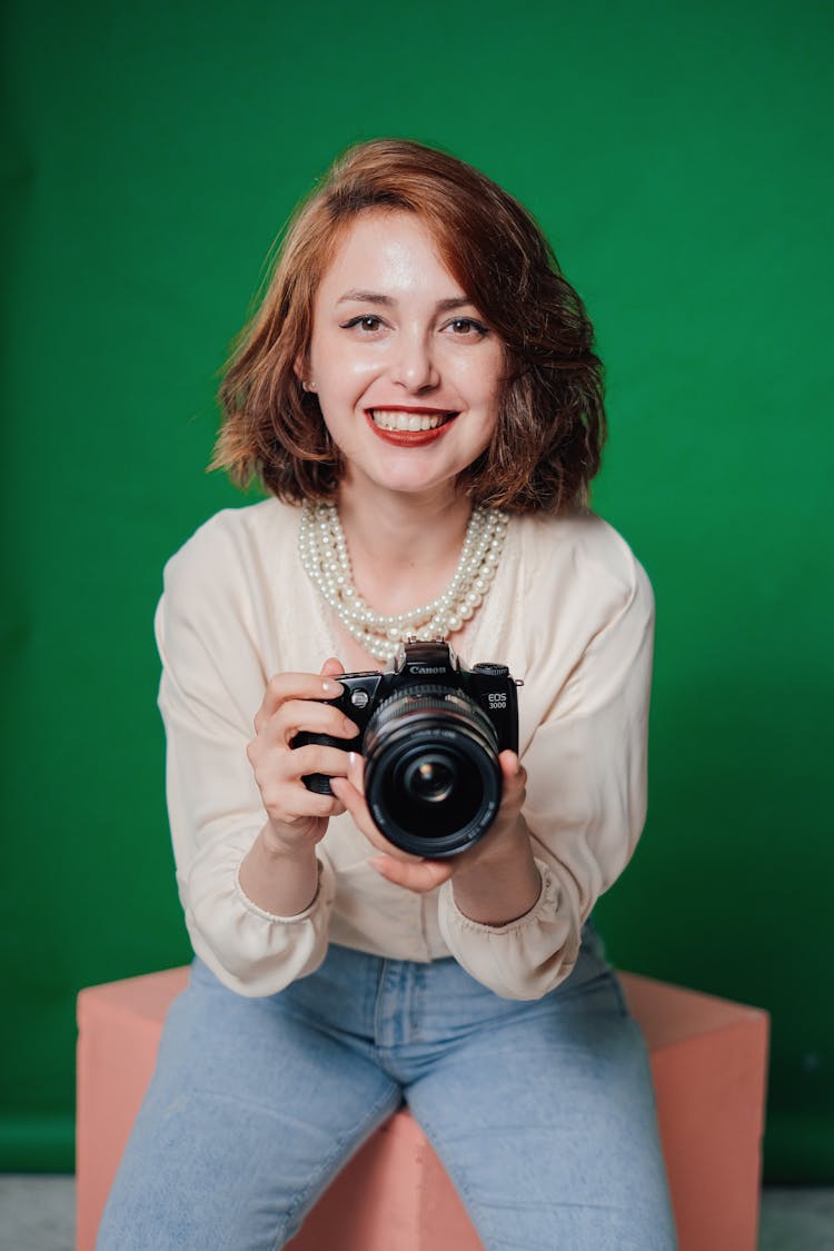 Studio Portrait Of Woman Wearing Pearls And Holding A Camera