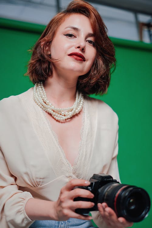 Portrait of a Woman in Red Lipstick and Pearl Necklace Holding a Camera