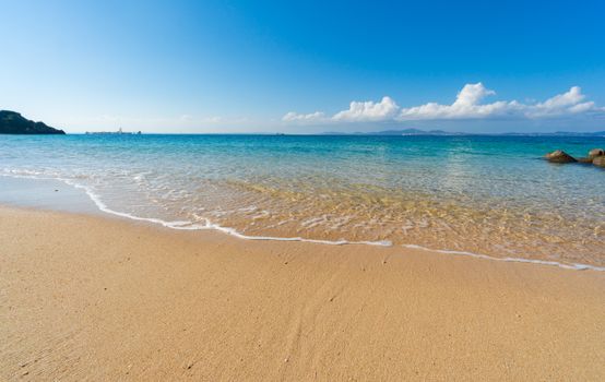 A serene beach scene with golden sands, clear waters, and blue skies, perfect for relaxation and nature appreciation.