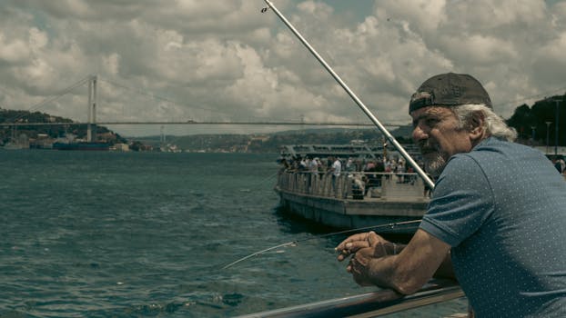 A man with a fishing rod along the Bosphorus by the bridge, Istanbul.