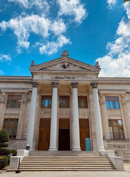 Impressive neoclassical facade with columns under a bright blue sky.