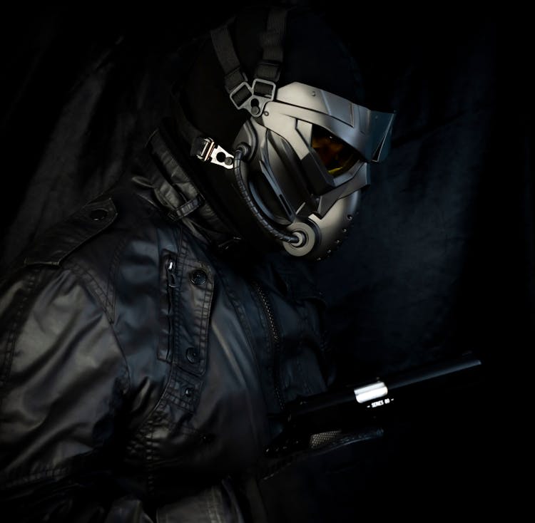 A Person In A Mask And Black Outfit Holding A Gun