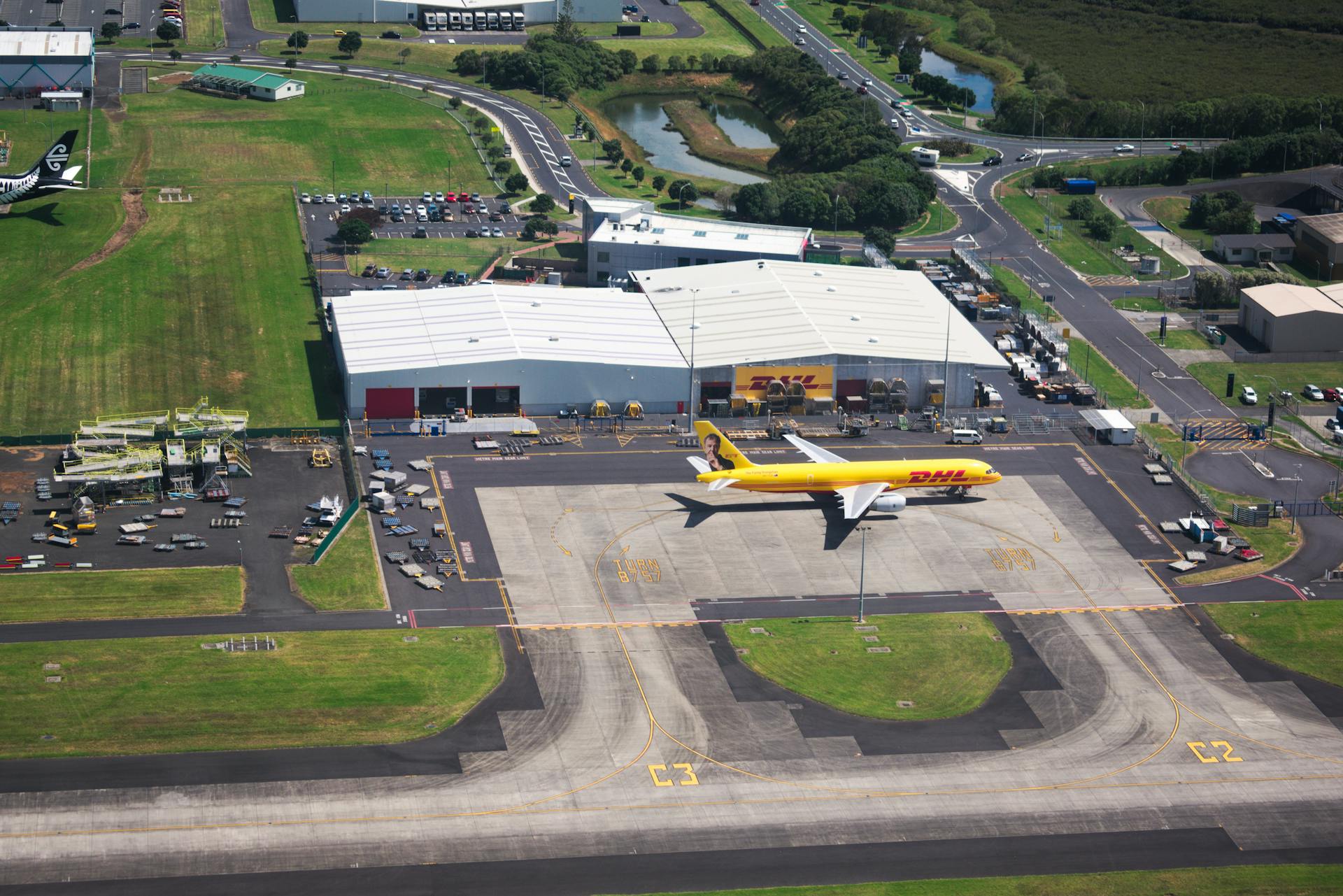 Aerial photo showcasing DHL airplane and hangar facilities in a busy airport setting.