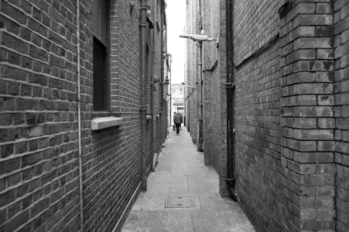 Free Grayscale Photo of People Walking Between Buildings  Stock Photo