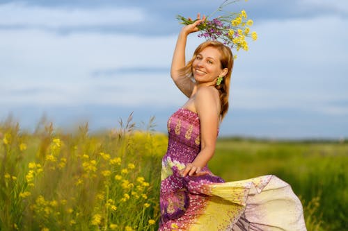 A Happy Woman in a Dress Holding a Bunch of Flowers