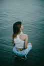 Woman in White Tank Top and Blue Denim Shorts Sitting on Rock by the Sea during