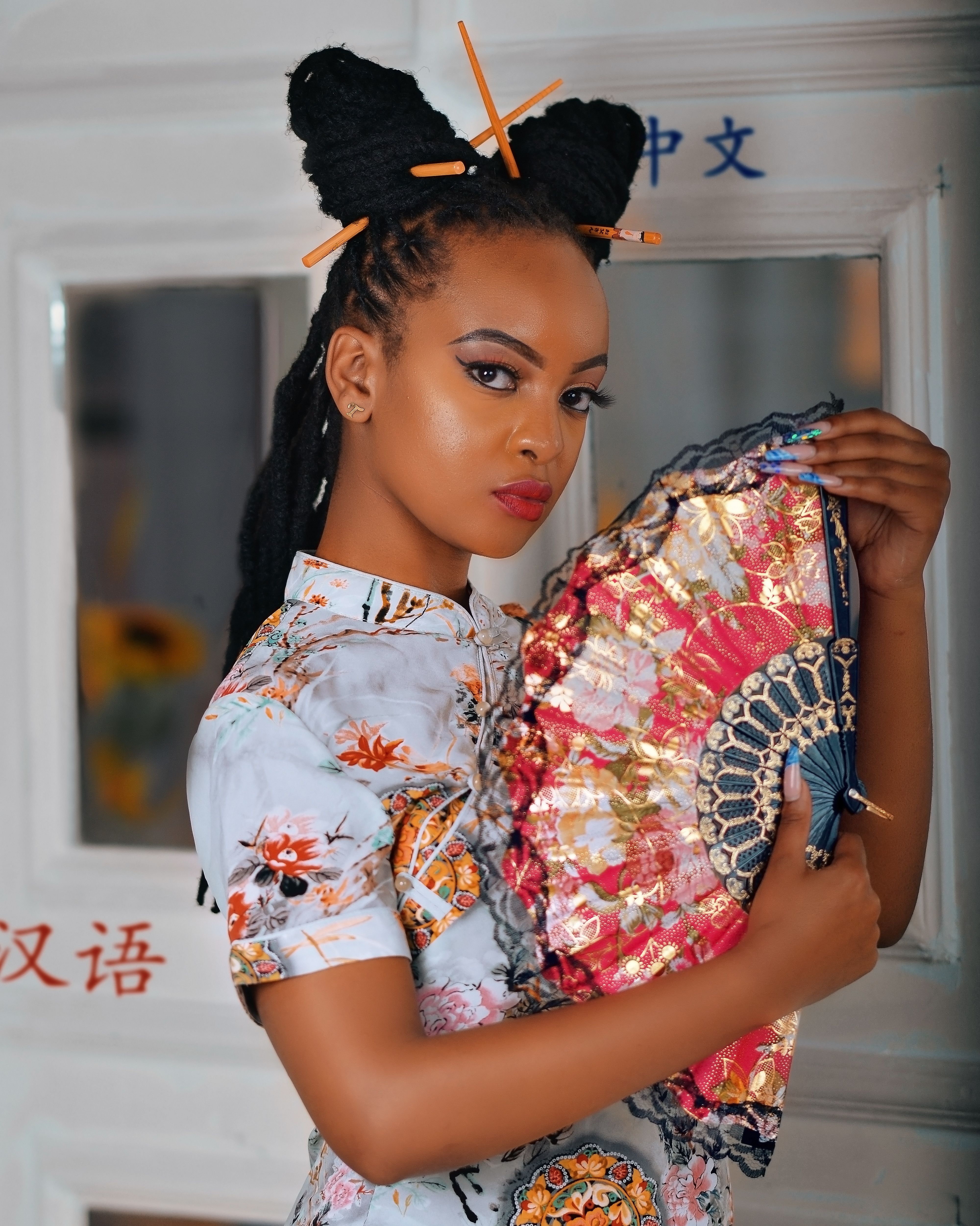 Portrait of an elegant woman in a traditional floral dress holding a colorful fan.