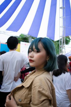 一位染着时尚发色的年轻女子在条纹树冠下的户外活动中摆姿势