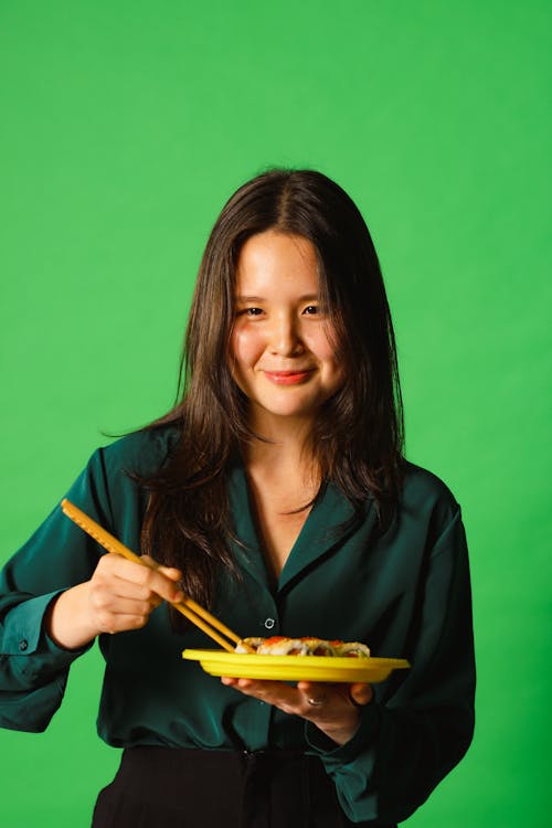 Woman in a Green Long Sleeves Holding Chopsticks and a Plate of Food