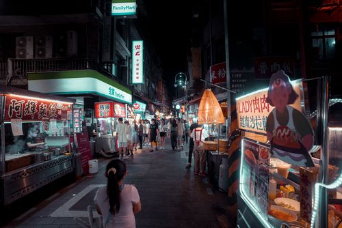 Free Bustling night market with diverse street food stalls and people shopping under vibrant lights. Stock Photo