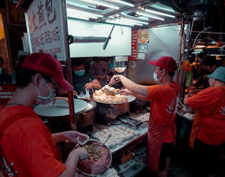 Street food vendors preparing and serving dumplings at an outdoor market at night.