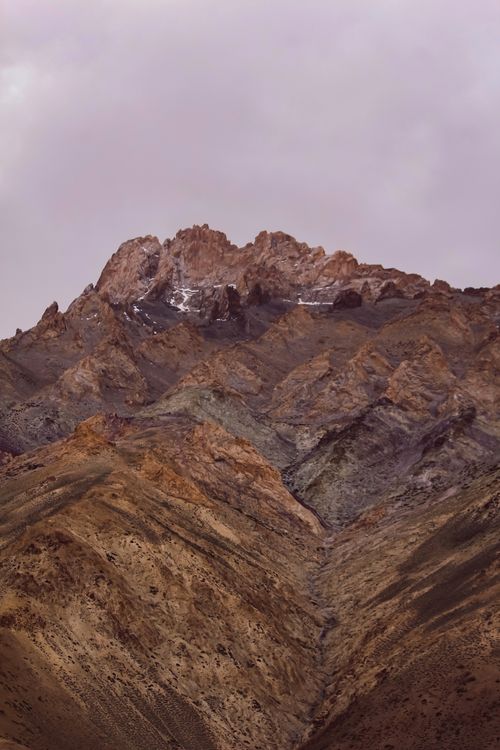 Free A breathtaking view of a rugged mountainous landscape with a rocky peak under a moody gray sky. Stock Photo