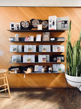 Neatly organized coffee shop shelves featuring products, decor, and a potted plant against a wooden backdrop.