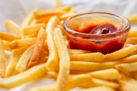 Close-up of crispy French fries served with a bowl of ketchup for dipping.