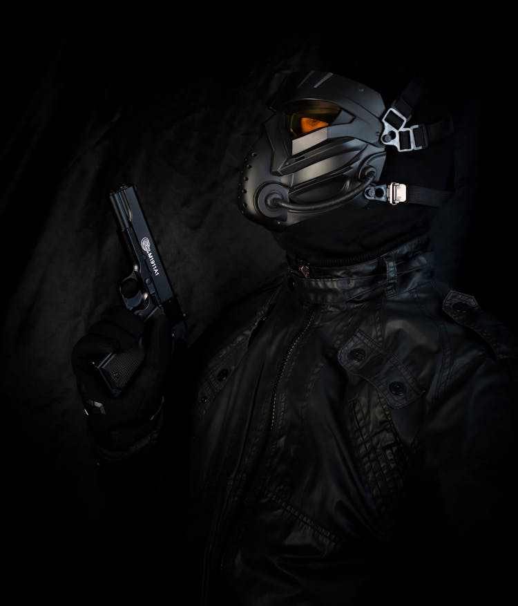 A Man In Black Jacket And Mask Holding A Handgun