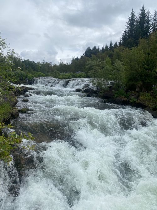 Free A dynamic waterfall flows through lush greenery capturing nature's beauty and power in a tranquil setting. Stock Photo