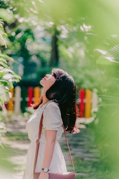 阳光明媚的花园里，一个女人正享受着宁静的时刻，周围环绕着郁郁葱葱的绿色植物