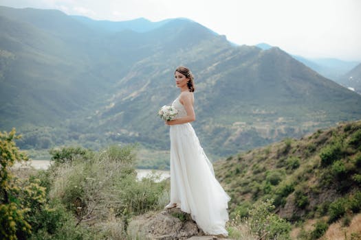A beautiful bride in a white dress holding a bouquet, surrounded by majestic mountains, perfect for outdoor wedding themes.