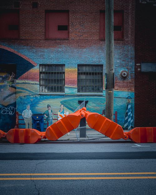 Free Colorful mural on a city street in Raleigh, NC, showcasing local art with vibrant orange barriers. Stock Photo