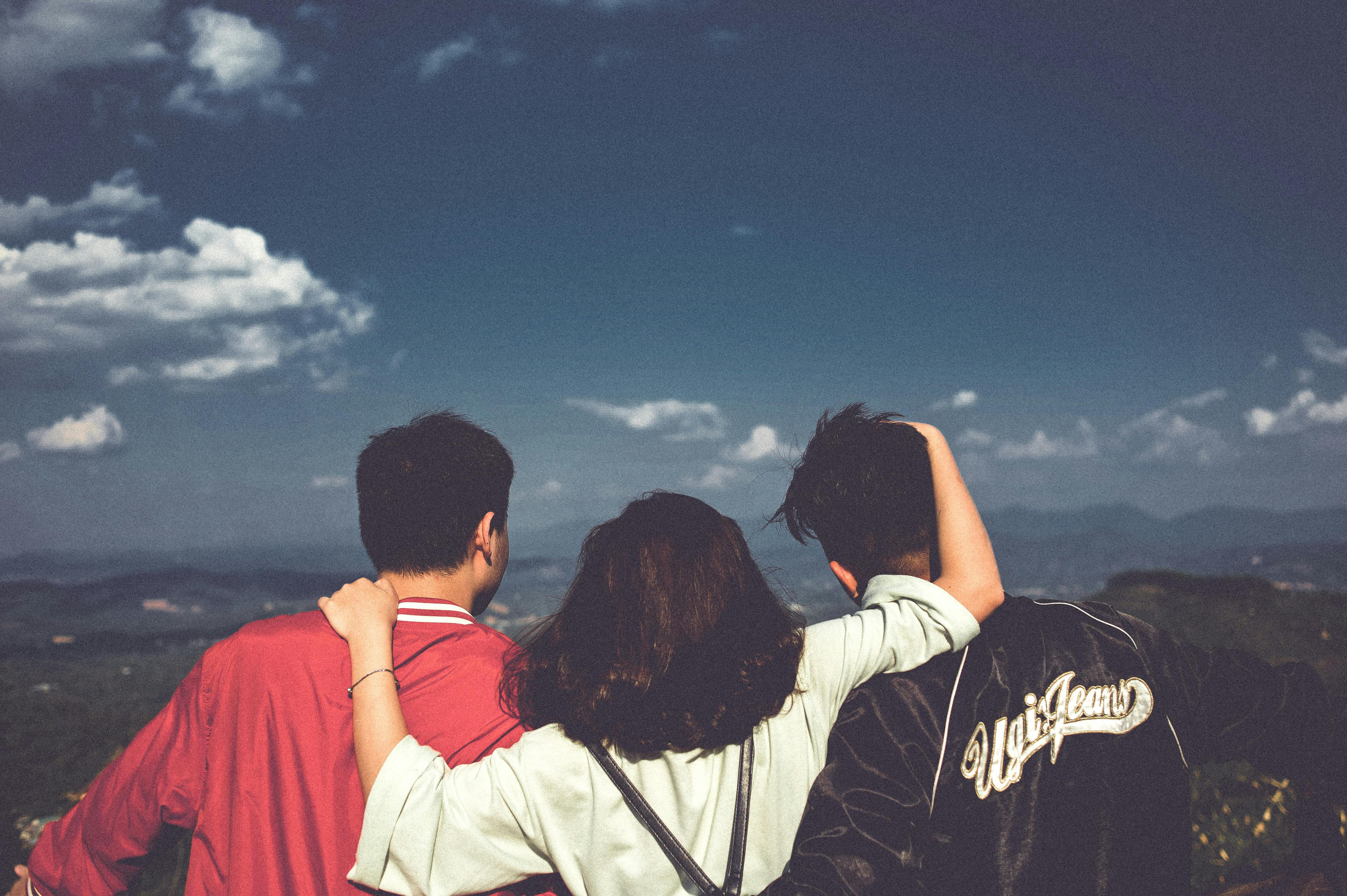 Woman Between Men Facing Mountains · Free Stock Photo