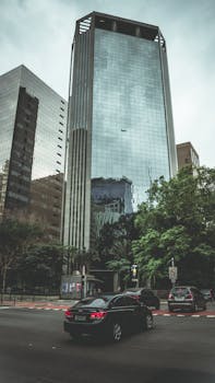 Tall glass skyscraper with reflections in a bustling urban environment.