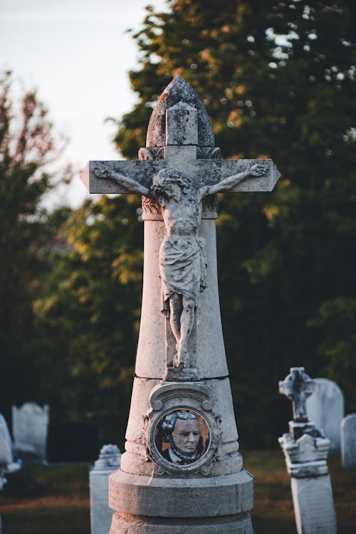 Free Statue on a Cross on a Gravestone Stock Photo