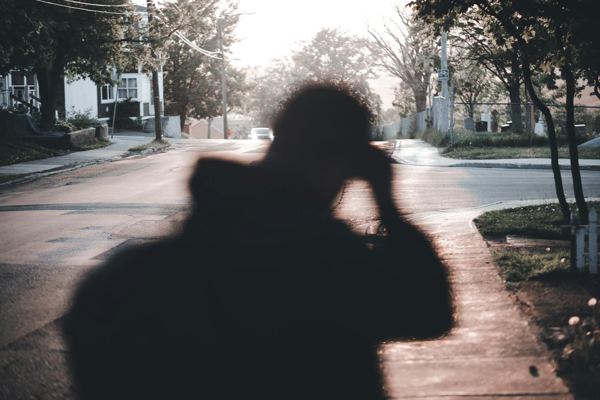 Blurred silhouette of a person on a quiet suburban street during sunrise, capturing a serene morning ambiance.