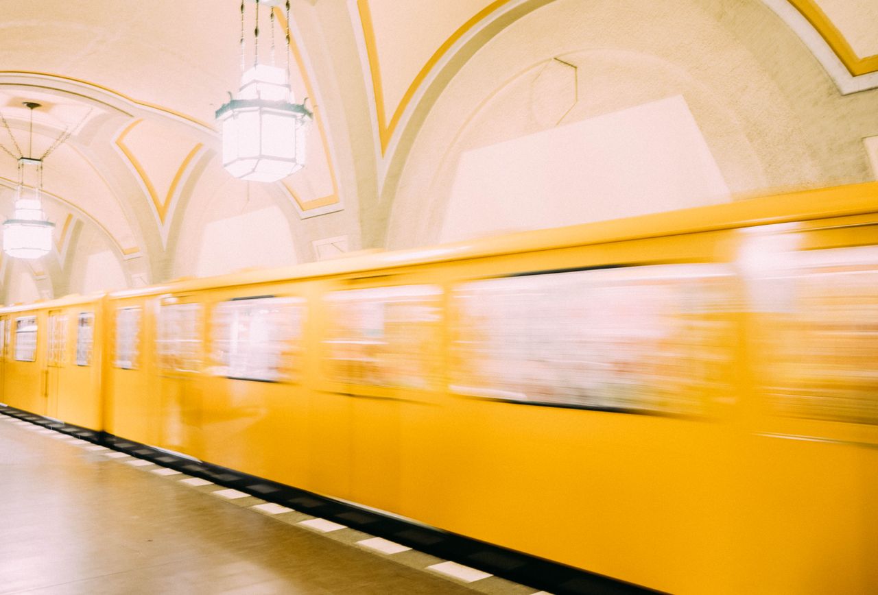 a vibrant yellow train speeds through a berlin subway station showcasi