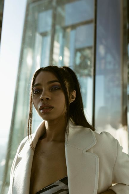 Modern portrait of a young woman with a city backdrop, evoking a stylish urban vibe.