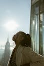 Woman in White Coat Standing Near Glass Window