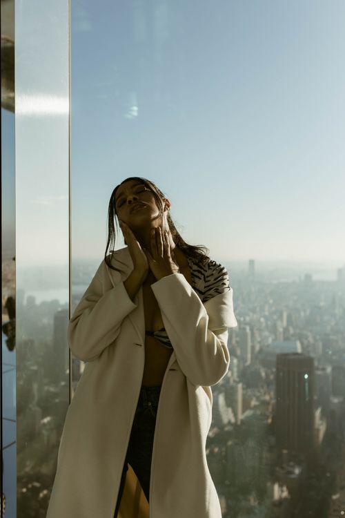 Free Elegant woman posing in front of New York City skyline with a reflective background. Stock Photo
