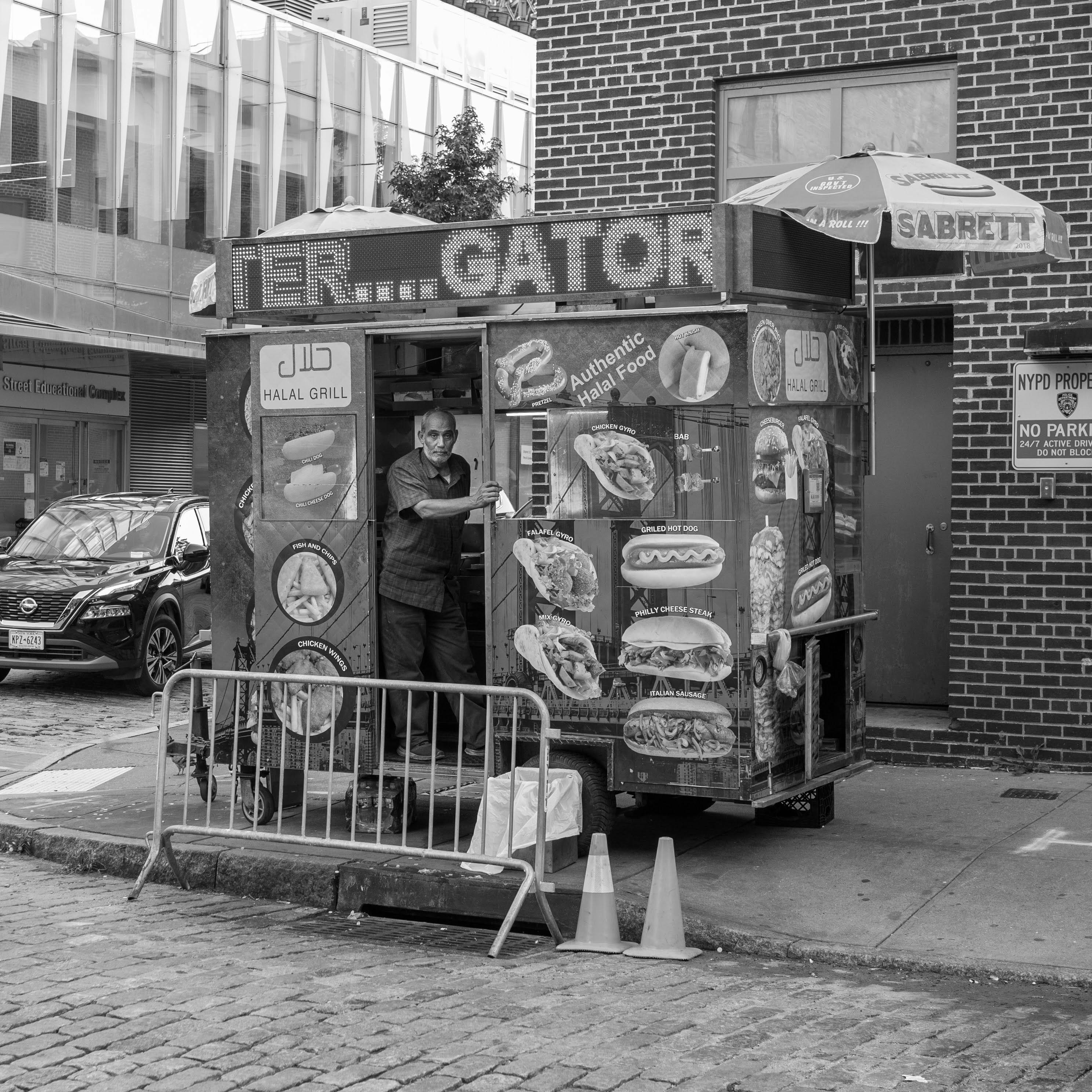 grayscale photo of a man standing inside the food truck